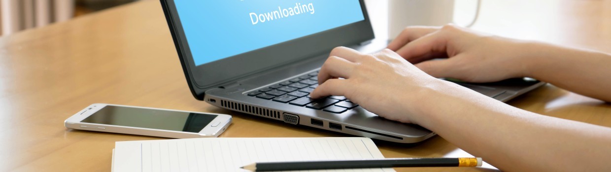Eine Person sitzt an einem Laptop der auf dem Monitor "Download" anzeigt.