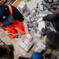 Ein Handwerker arbeitet mit Steinen an einer Grundfläche.