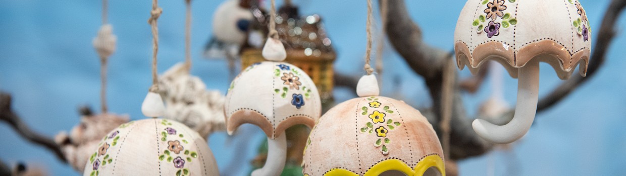 Regenschirme aus Keramik hängen von einem Baum herunter.