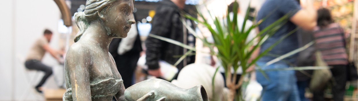 Eine Statue einer Frau kippt eine Vase mit Wasser aus.